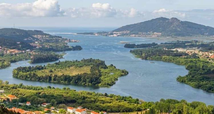 Paysage d'estuaire étendu où un fleuve sinueux rencontre l'Atlantique, encadré par des montagnes et des îles verdoyantes.