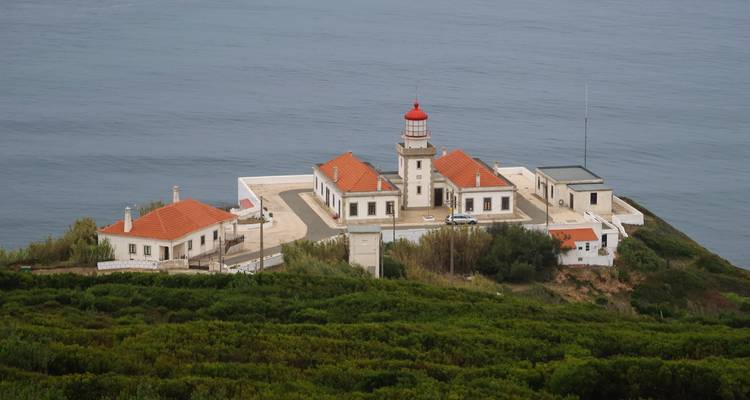 Un complexe de phares côtiers aux toits de tuiles rouges se dresse au sommet d'une falaise verdoyante dominant l'Atlantique.