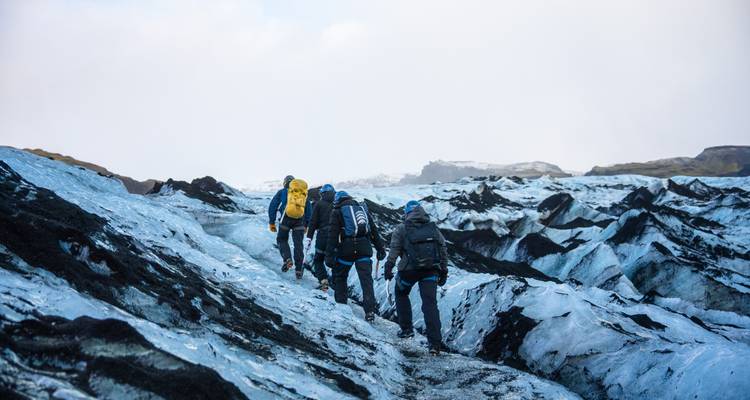 Groupe de randonneurs encordés lors de l'ascension d'un glacier bleu dans les hautes terres accidentées d'Islande.