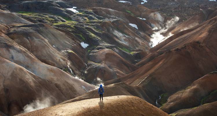 Randonneur solitaire contemplant les vallées volcaniques fumantes et multicolores de Landmannalaugar.