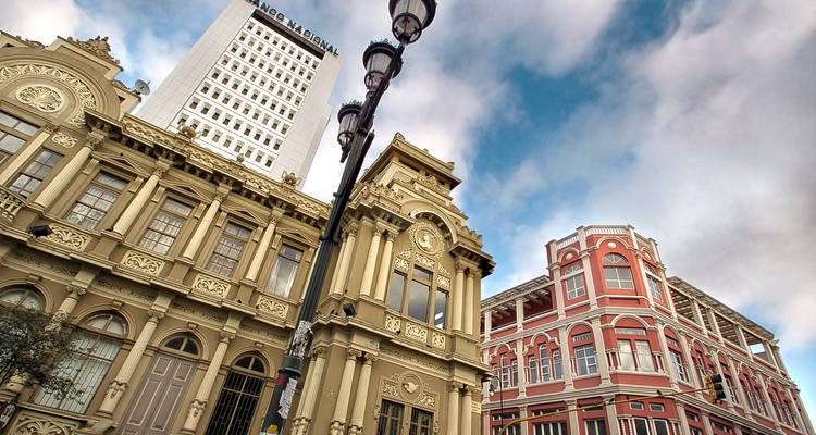 Historic and modern buildings in downtown San José with dramatic sky and tall lamp post