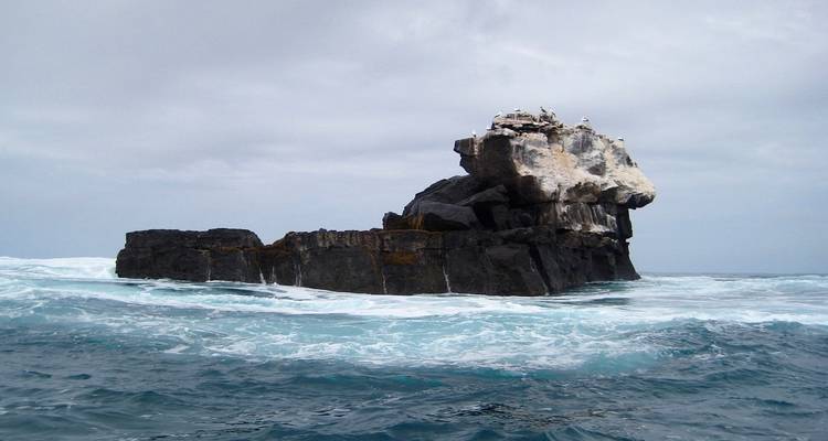 Große Felsformation im Ozean, umgeben von Wellen.