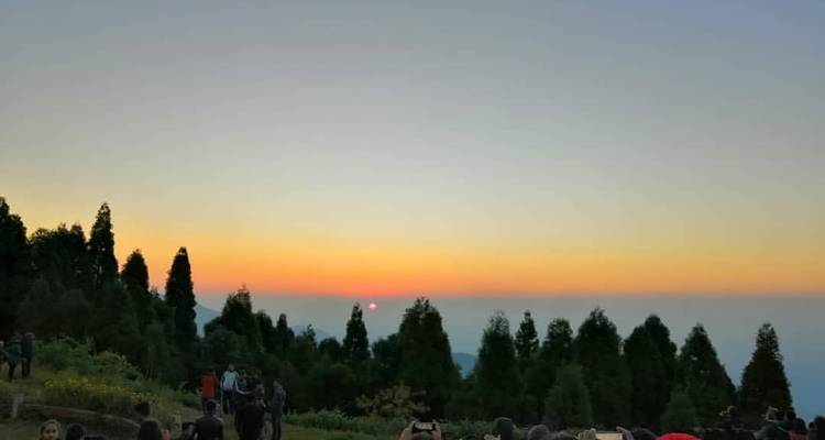 Gente observando un atardecer sobre las montañas.