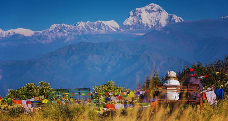 Mensen die op bankjes zitten met uitzicht op het Himalayagebergte.