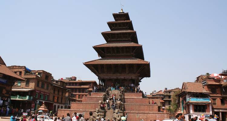 Foule devant un grand temple à gradins aux détails complexes.