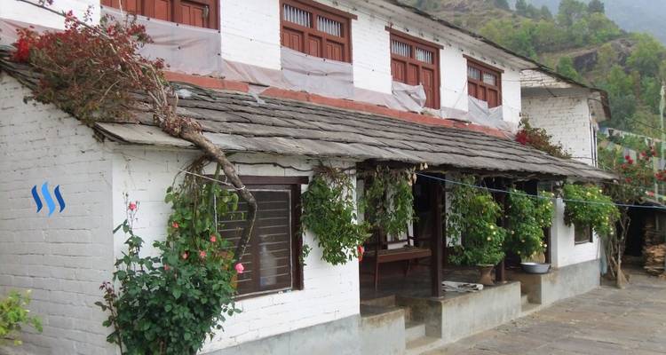 Traditionelles Haus mit hängenden Pflanzen und einer bergigen Kulisse.