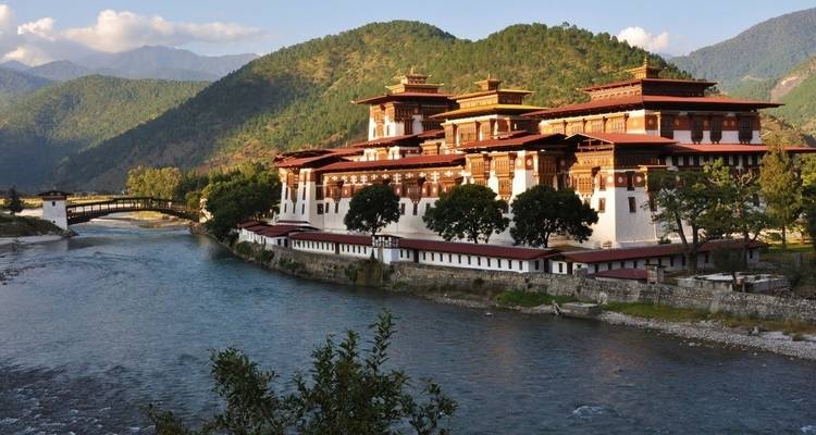 Punakha Dzong au bord d'une rivière avec un paysage de montagne en arrière-plan.