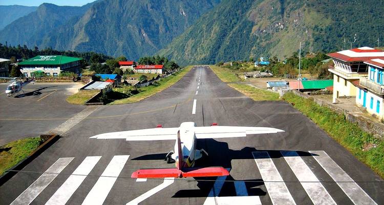 Airplane on a mountain runway with scenic valley view.