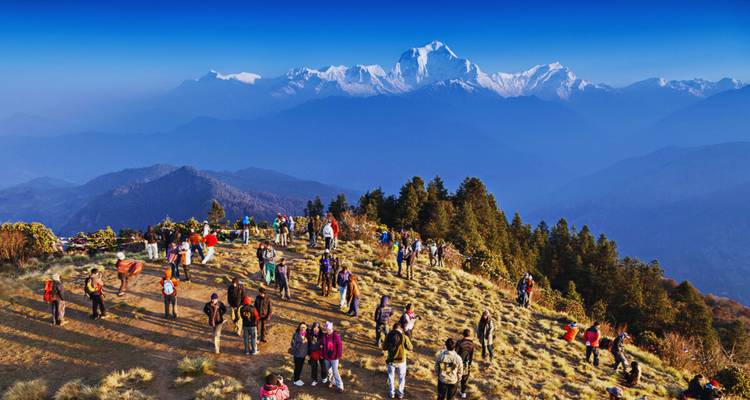 Un groupe de personnes rassemblées sur une colline avec une vue panoramique sur l'Himalaya.