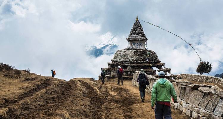 Randonneur marchant vers un stupa avec des drapeaux de prière.