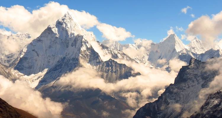 Montagnes enneigées avec des nuages dans un ciel clair.