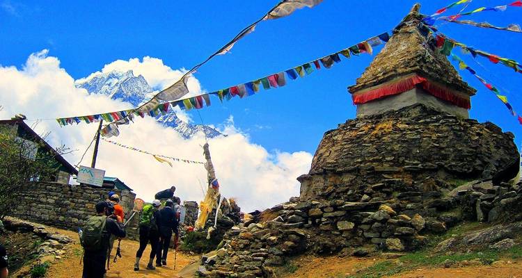 Des randonneurs s'approchant d'un stupa avec des montagnes en arrière-plan.
