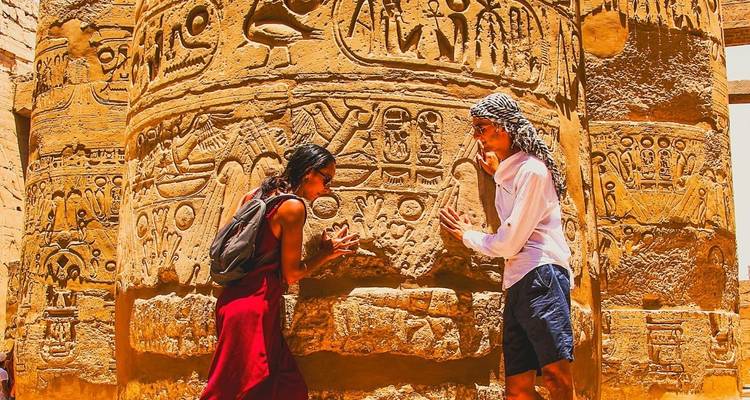 Deux personnes explorant des hiéroglyphes sur d'anciens piliers.