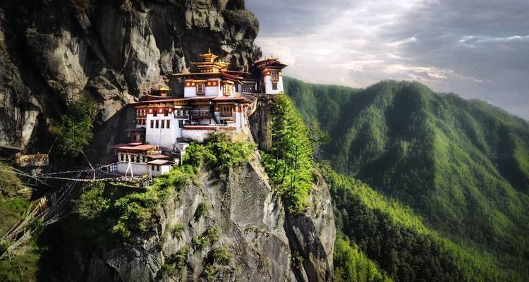 Zicht op het Tijgernest Klooster gelegen op een klif in een weelderig, bergachtig landschap.