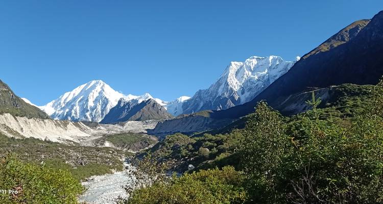 Vue spectaculaire de montagnes enneigées et de vallées sous un ciel bleu clair.