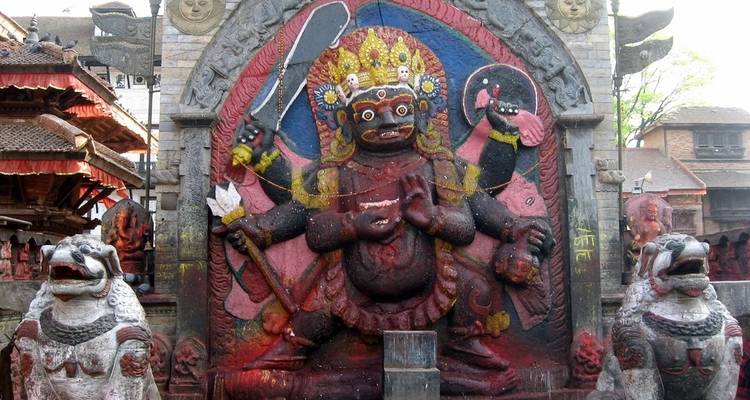 Steenbeeldhouwwerk van een godheid met meerdere armen en twee stenen leeuwen.