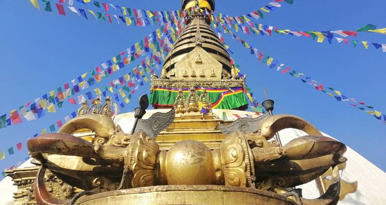 Goldene Stupas mit Gebetsfahnen unter einem blauen Himmel.