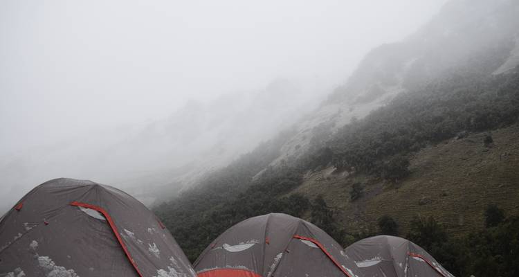 Tents in foggy mountain landscape.