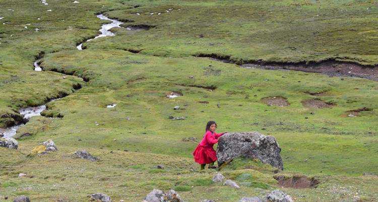 Child in red dress in a green landscape.