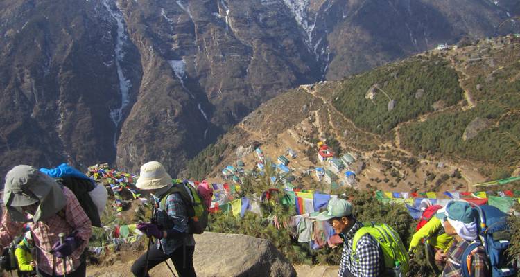 Randonneurs avec des sommets montagneux et des drapeaux de prière en vue.