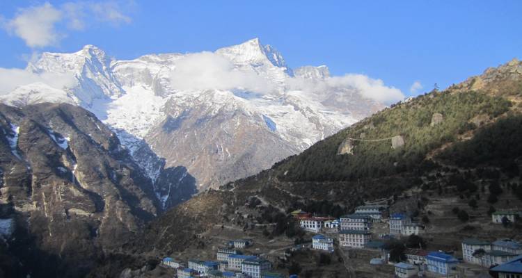 Vue lointaine d'un village de montagne avec des sommets enneigés.