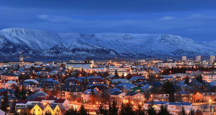 Aerial view of Reykjavik with mountainous backdrop at twilight.