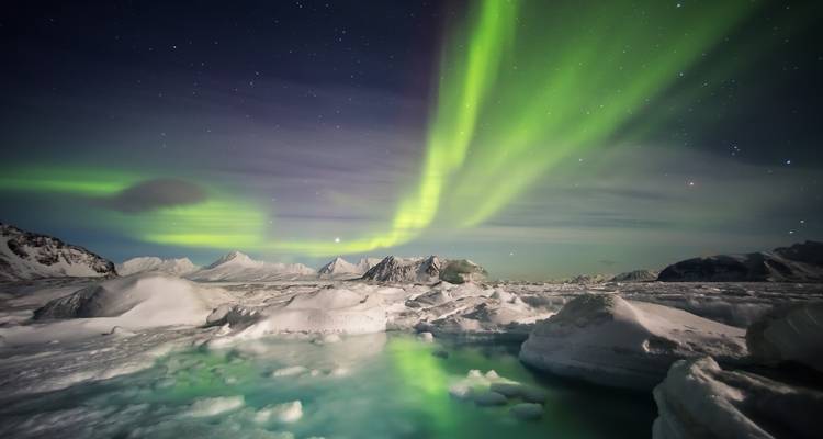 Aurora borealis over a snow-covered landscape at night.