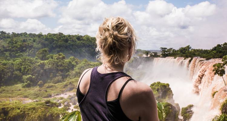 Personne debout près d'une grande cascade.
