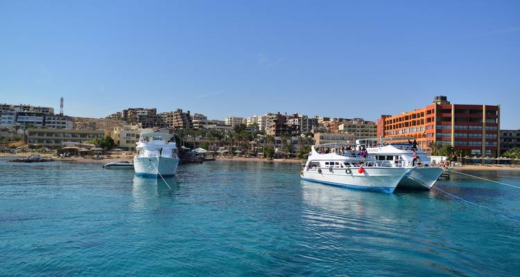 Boats docked near apartment buildings by the sea.