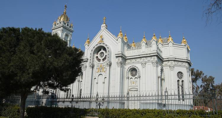 Una iglesia blanca con cúpulas doradas y arquitectura detallada en un día despejado.