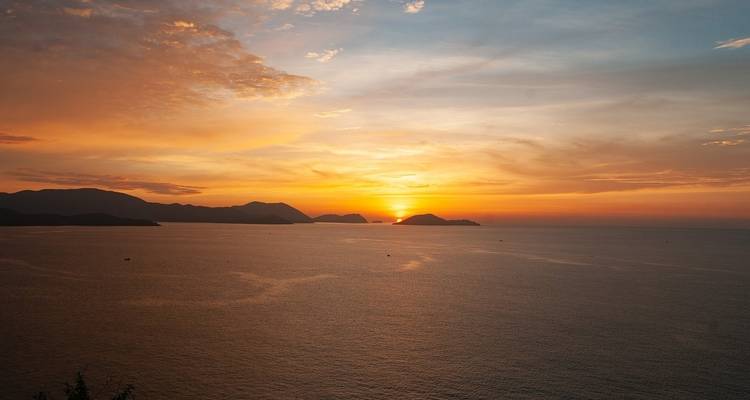 Schöner Sonnenuntergang über dem Ozean mit Inseln in der Ferne.
