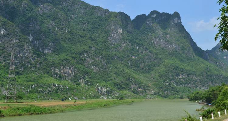 Breiter Fluss mit bewaldeten Klippen auf beiden Seiten unter blauem Himmel.