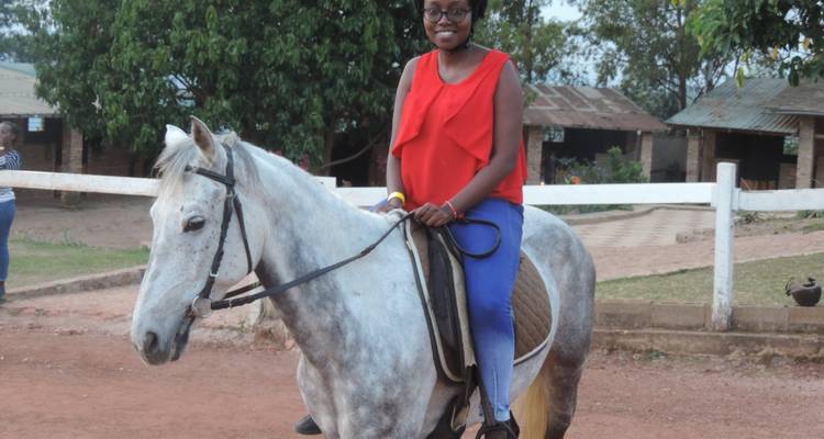 Personne assise sur un cheval blanc dans un espace ouvert avec des arbres.