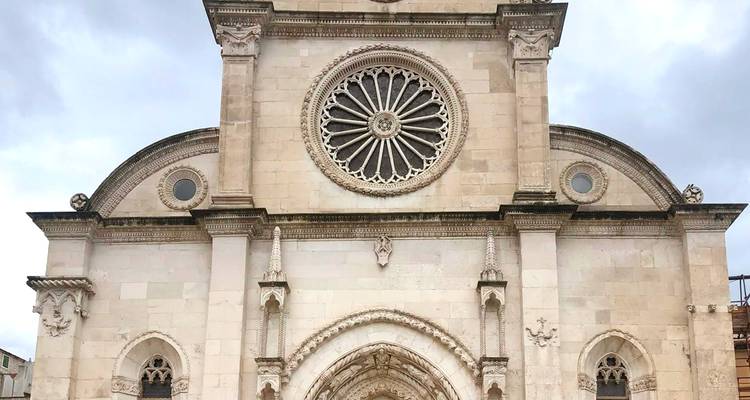Vista frontal simétrica de la Catedral de Sibenik destacando su rosetón y los detalles góticos.
