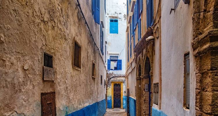 Ruelle étroite avec des bâtiments bleus et blancs dans une ville historique.