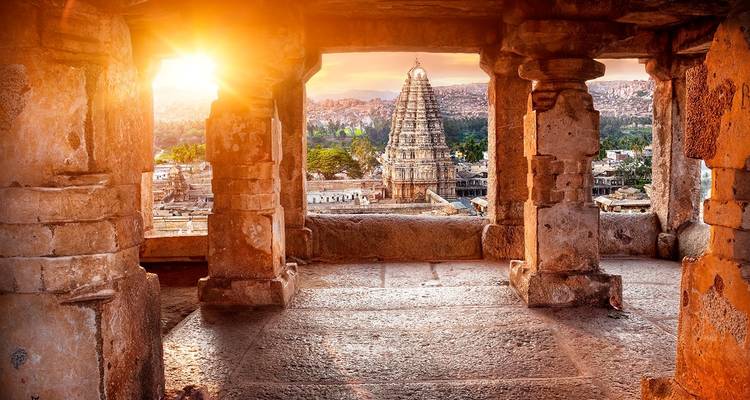Virupaksha Temple in Hampi at sunset viewed from stone archway.