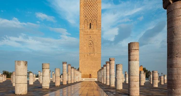 Tour entourée de colonnes sur une place carrelée sous un ciel bleu.