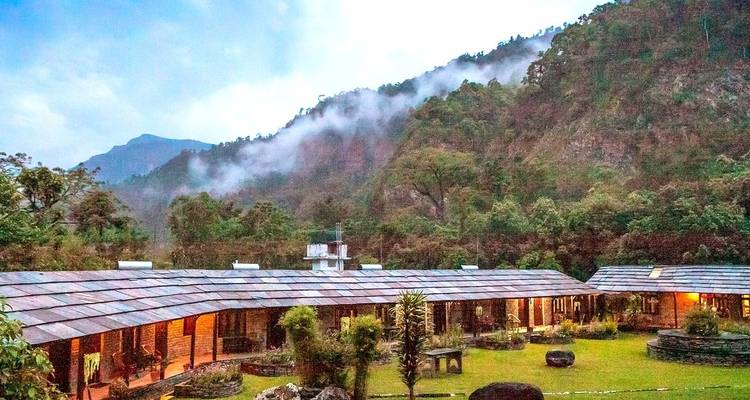 Rustic lodges with misty hills in the background.