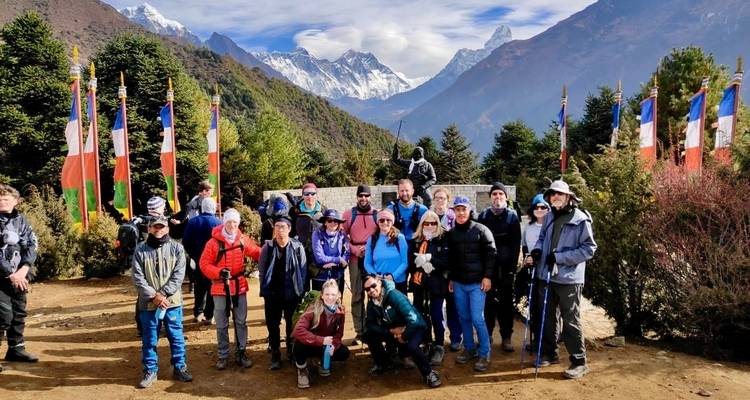 Group of trekkers posing with snowy mountains in the background.