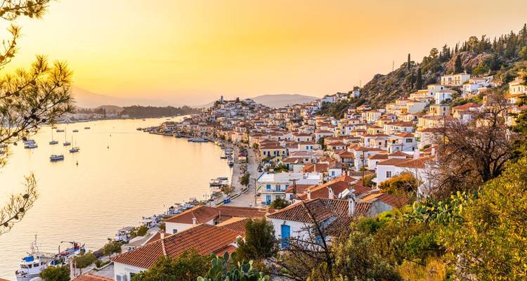 Ville côtière pittoresque au coucher du soleil avec des bâtiments aux toits rouges.