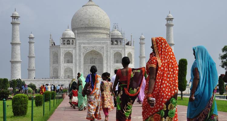 Visitantes caminando hacia el Taj Mahal, algunos vestidos con ropa colorida.
