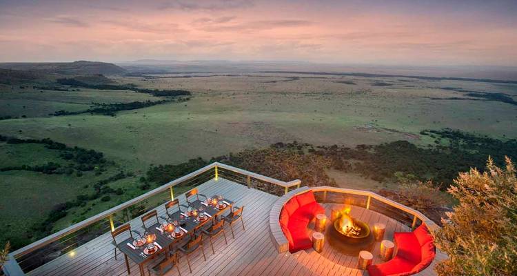 Outdoor dining area overlooking vast plains at sunset.