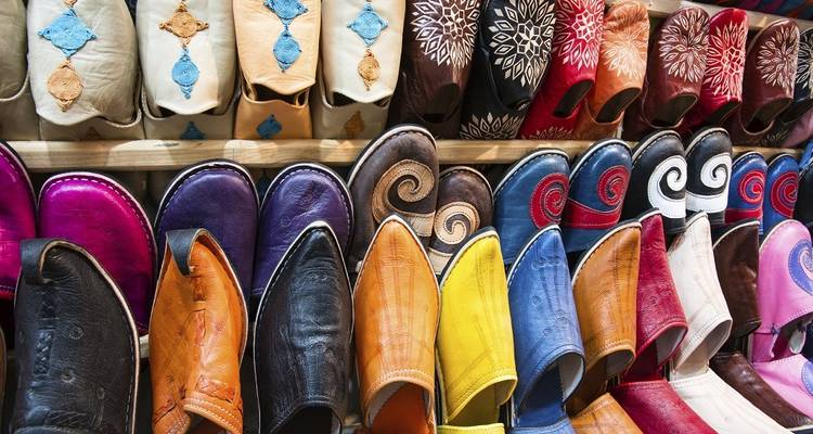 Reihe von leuchtend gefärbten traditionellen marokkanischen Lederpantoffeln, die in einem Souk ausgestellt sind.