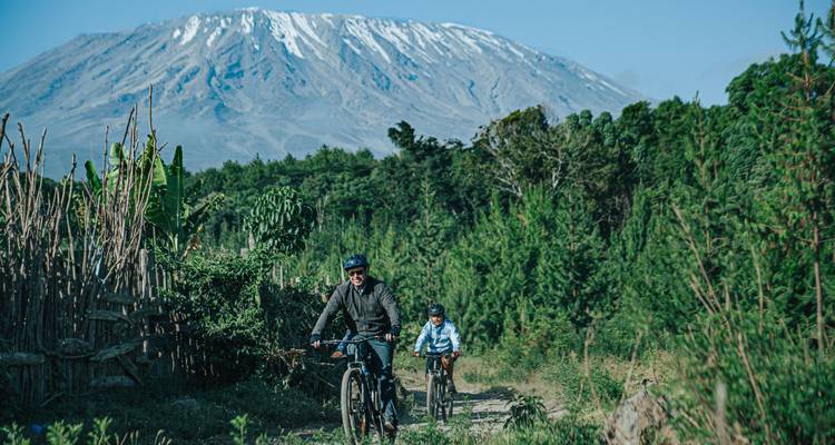 Cyclists on a trail with a close view of Mount Kilimanjaro.