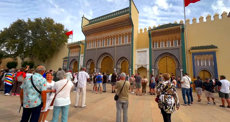 Menigten verzamelen zich buiten de sierlijke mozaïekpoort van het Koninklijk Paleis in Fes versierd met Marokkaanse vlaggen.