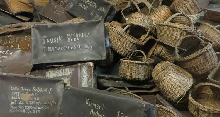 Pile of worn luggage and baskets with names written on them.