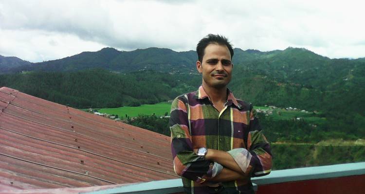 Persoon die poseert voor een bergachtige achtergrond.