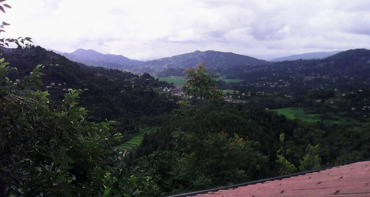 Heuvelachtig landschap met een uitzicht op een dorp in de verte en een dak.