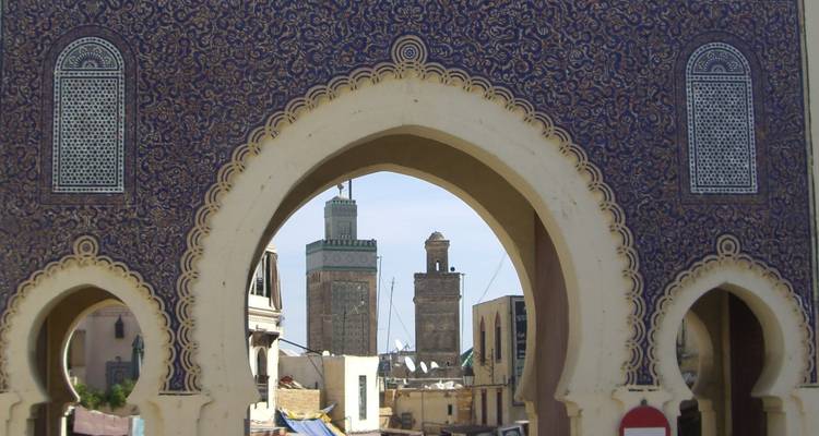 View through an ornate archway to minarets in the background.