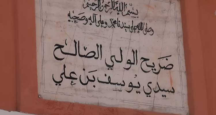 Arabische inscriptieplaquette gemonteerd op een oranje muur.